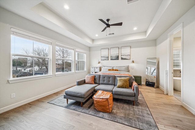 bedroom featuring a raised ceiling, ceiling fan, and light wood-type flooring