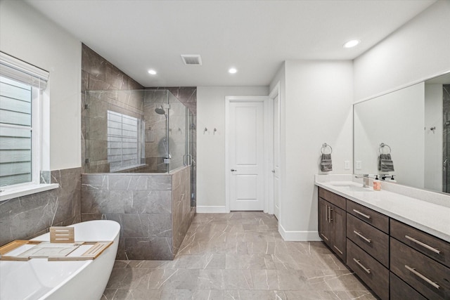 bathroom with vanity, shower with separate bathtub, and tile walls