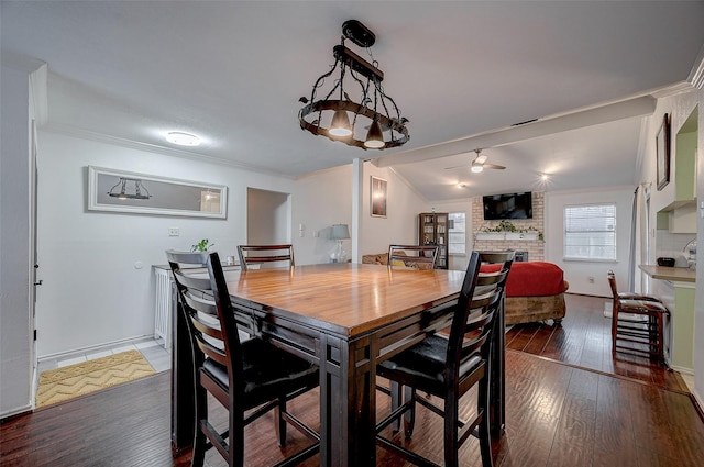 dining space featuring vaulted ceiling, dark hardwood / wood-style floors, ornamental molding, ceiling fan, and a brick fireplace