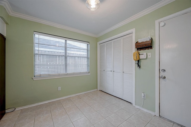 unfurnished bedroom with light tile patterned floors, crown molding, and a closet