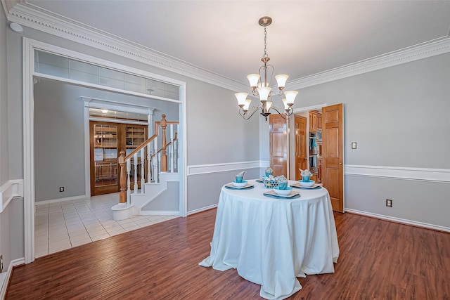 dining area with wood-type flooring, a notable chandelier, and crown molding