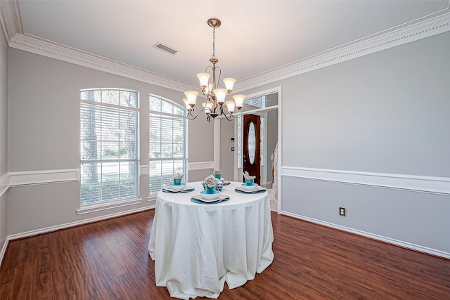 unfurnished dining area featuring an inviting chandelier, ornamental molding, and dark hardwood / wood-style flooring