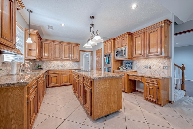 kitchen with a kitchen island, sink, hanging light fixtures, light tile patterned floors, and stainless steel appliances