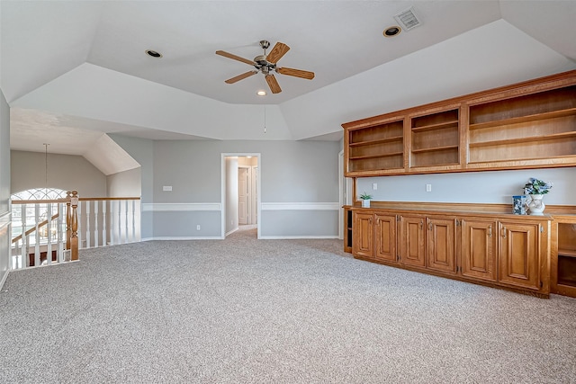 unfurnished living room with a raised ceiling, vaulted ceiling, light carpet, and ceiling fan