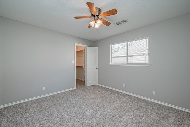 unfurnished bedroom with ceiling fan, a walk in closet, carpet flooring, and a closet