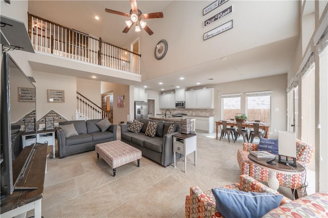 living room with ceiling fan, a towering ceiling, and sink