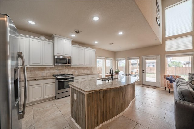 kitchen with appliances with stainless steel finishes, sink, an island with sink, and white cabinets