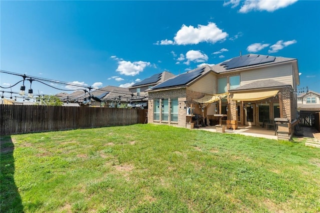 rear view of house with a yard, a patio area, and solar panels