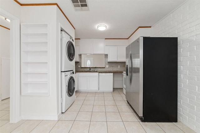 kitchen with light tile patterned flooring, stacked washer and clothes dryer, stainless steel fridge with ice dispenser, white dishwasher, and white cabinets