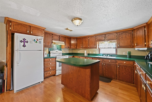 kitchen featuring sink, white appliances, light hardwood / wood-style flooring, a center island, and a textured ceiling