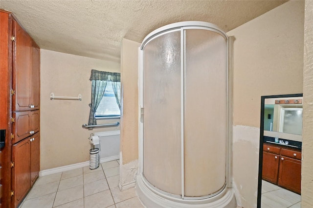 bathroom with a shower with door, vanity, tile patterned flooring, and a textured ceiling