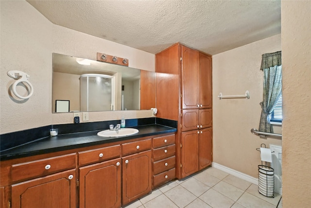 bathroom featuring tile patterned floors, a shower with door, a textured ceiling, and vanity