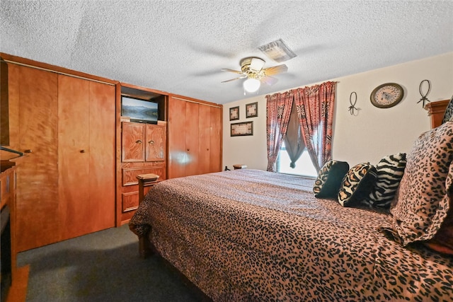 bedroom with ceiling fan, two closets, a textured ceiling, and carpet