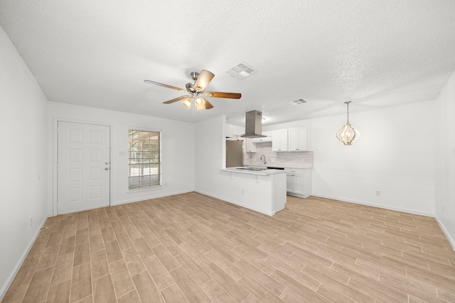 unfurnished living room with ceiling fan, a textured ceiling, and light hardwood / wood-style floors