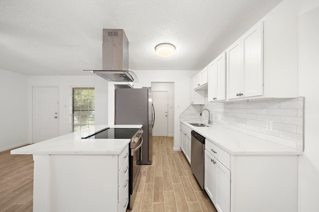 kitchen with sink, light stone counters, island range hood, stainless steel appliances, and white cabinets