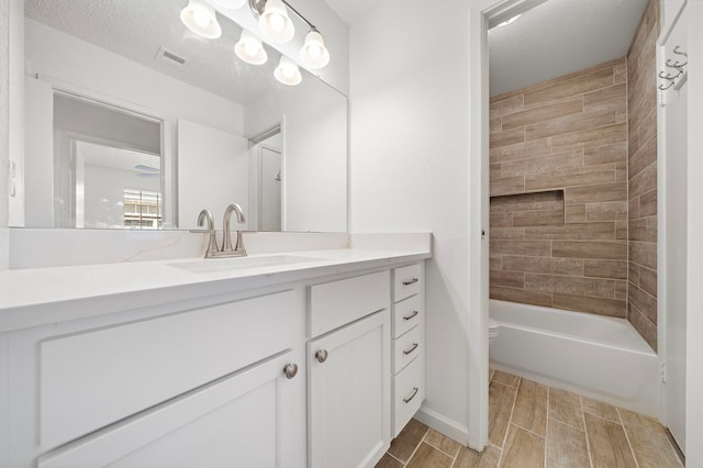 full bathroom with vanity, tiled shower / bath combo, toilet, and a textured ceiling