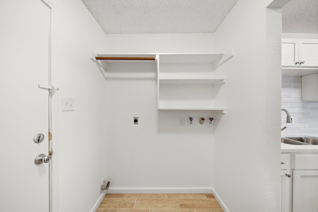 washroom featuring cabinets, sink, hookup for an electric dryer, and a textured ceiling