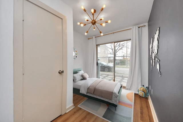 bedroom with a notable chandelier, light hardwood / wood-style flooring, and access to outside