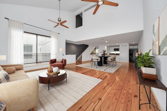 living room featuring ceiling fan, beam ceiling, high vaulted ceiling, and light hardwood / wood-style flooring