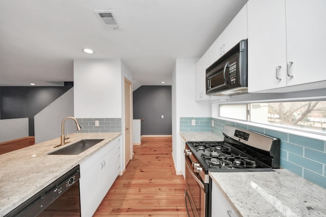 kitchen featuring sink, light stone counters, black appliances, white cabinets, and light wood-type flooring