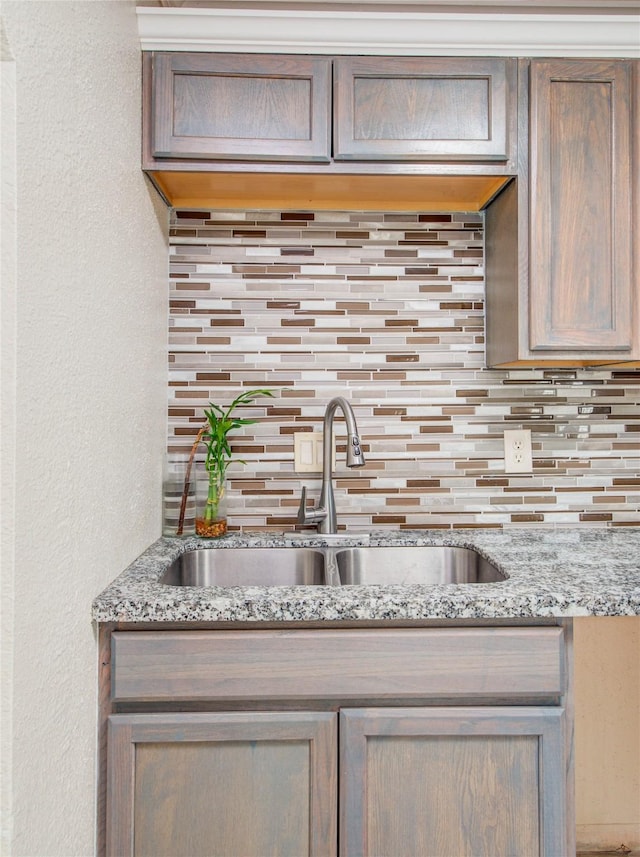 kitchen with sink, light stone counters, and decorative backsplash