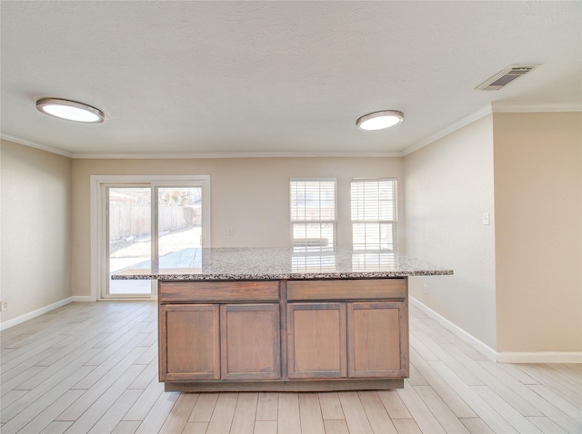 kitchen featuring a wealth of natural light, light stone counters, and light hardwood / wood-style flooring