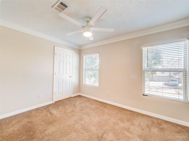 spare room with light carpet, ceiling fan, crown molding, and a textured ceiling