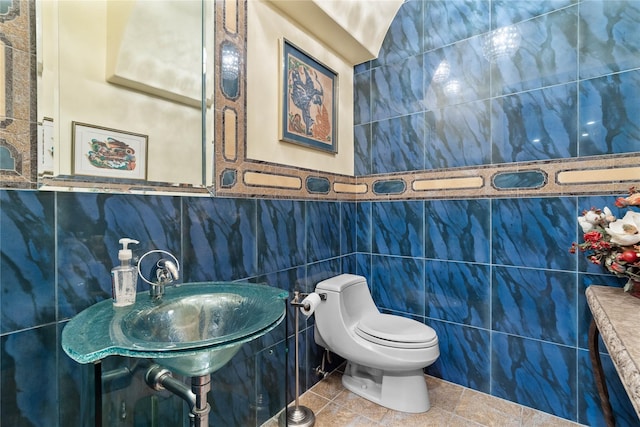 bathroom with toilet, tile patterned flooring, and tile walls