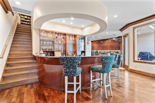 bar with ceiling fan and light hardwood / wood-style flooring