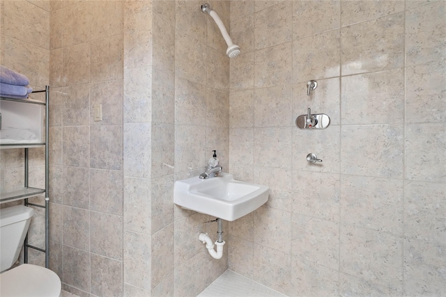 bathroom with toilet, sink, and a tile shower