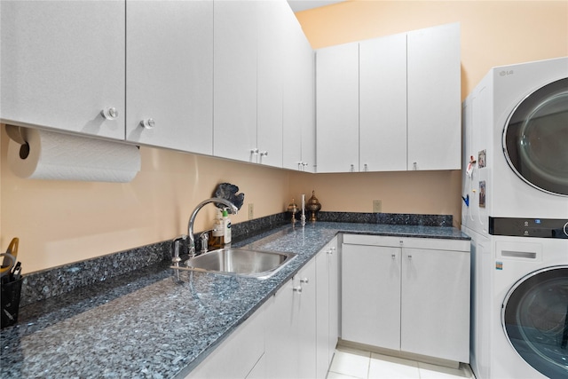 laundry room with stacked washer / dryer, sink, light tile patterned floors, and cabinets