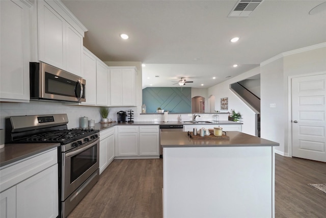 kitchen featuring tasteful backsplash, white cabinetry, dark hardwood / wood-style flooring, a center island, and stainless steel appliances