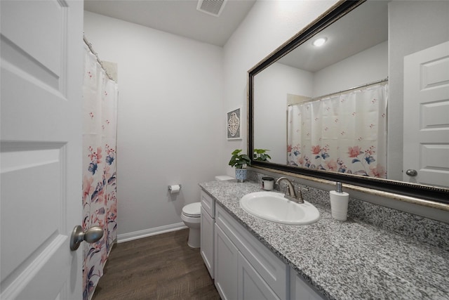 bathroom with hardwood / wood-style flooring, vanity, a shower with shower curtain, and toilet