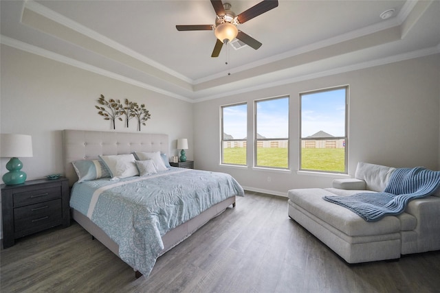 bedroom featuring dark wood-type flooring, ornamental molding, and a raised ceiling