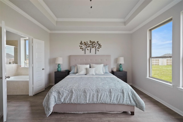 bedroom with ornamental molding, ensuite bath, dark hardwood / wood-style flooring, and a tray ceiling