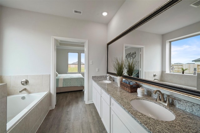 bathroom featuring vanity, hardwood / wood-style flooring, and tiled bath