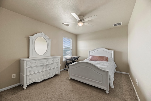 bedroom featuring ceiling fan, light colored carpet, and a textured ceiling