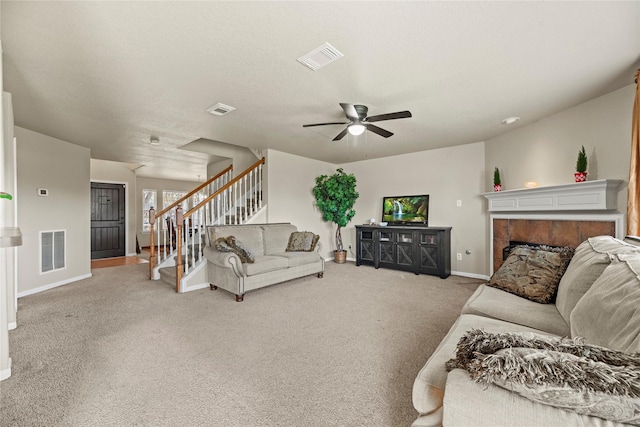 carpeted living room with ceiling fan, a fireplace, and a textured ceiling