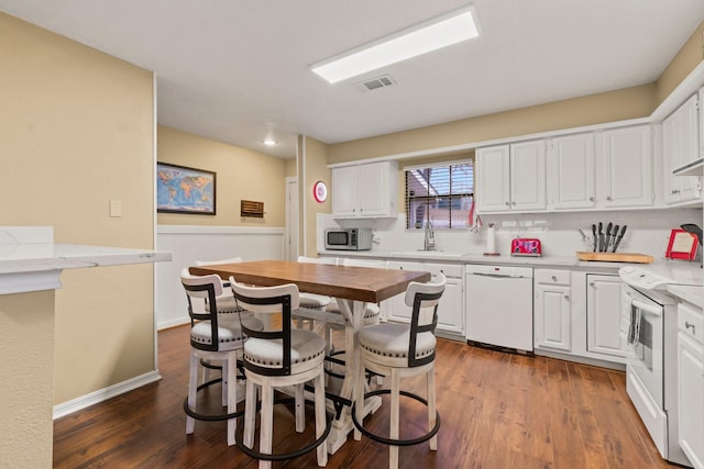 kitchen with white cabinetry, dark hardwood / wood-style flooring, sink, and white appliances