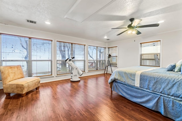 bedroom with ceiling fan, crown molding, dark hardwood / wood-style floors, and a textured ceiling