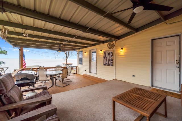 patio terrace at dusk featuring ceiling fan and a water view