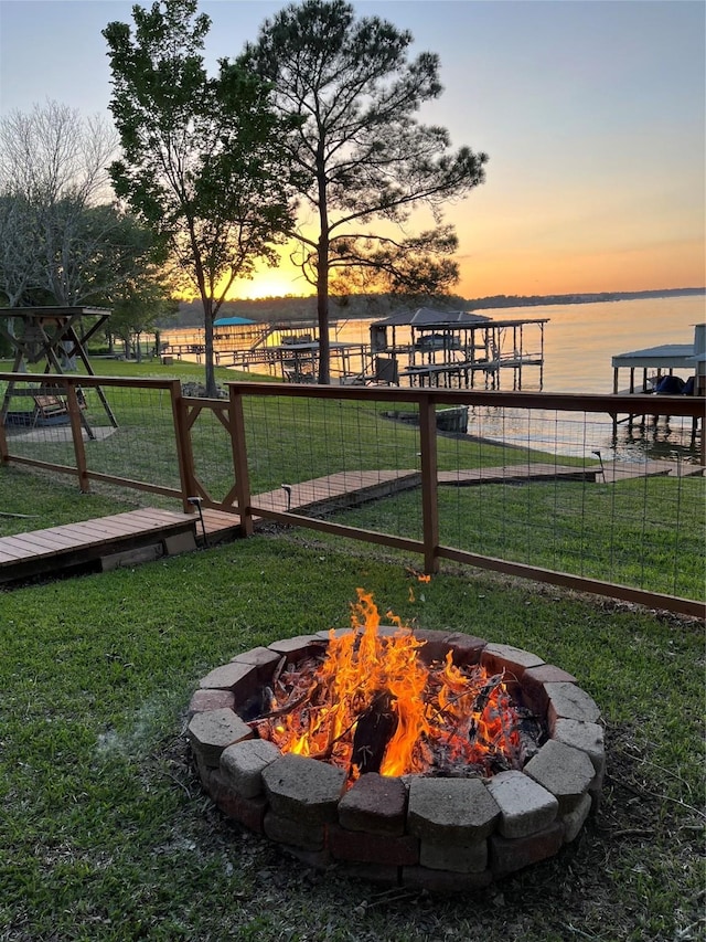 yard at dusk featuring a water view and an outdoor fire pit