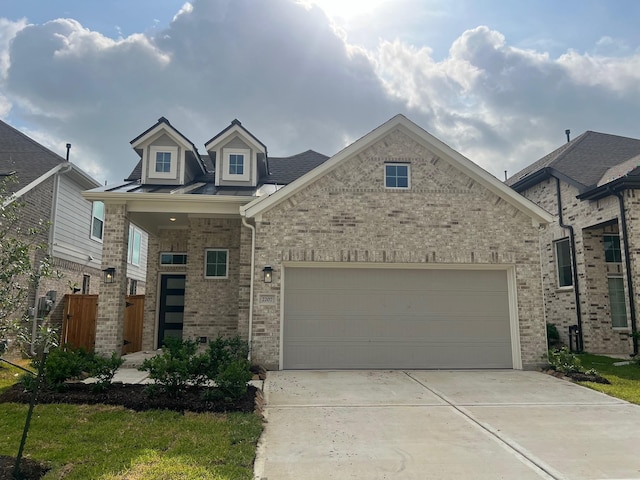 view of front of home featuring concrete driveway, an attached garage, brick siding, and fence