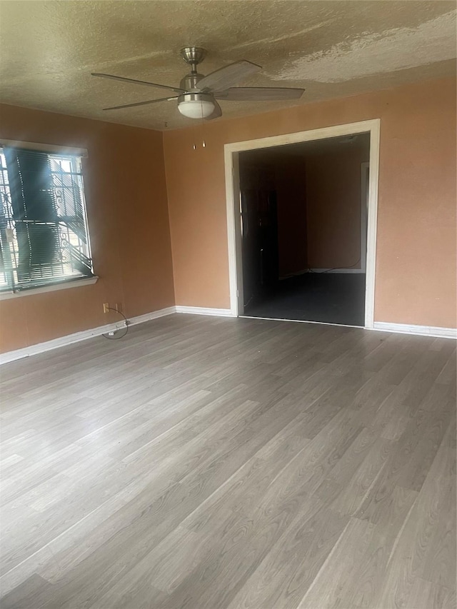 empty room featuring ceiling fan, hardwood / wood-style floors, and a textured ceiling