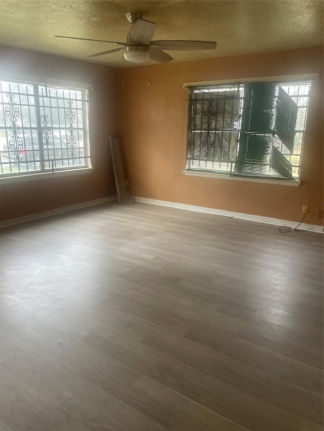 unfurnished room featuring hardwood / wood-style flooring, ceiling fan, and a textured ceiling