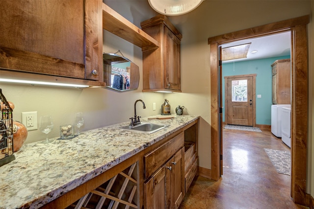 kitchen featuring washer and clothes dryer, sink, and light stone countertops