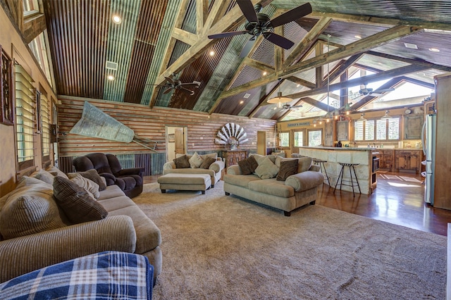 living room featuring ceiling fan, hardwood / wood-style floors, beam ceiling, high vaulted ceiling, and log walls