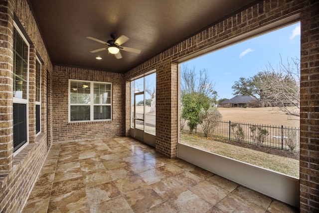 unfurnished sunroom featuring ceiling fan