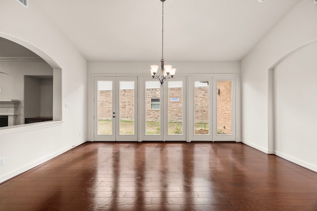 unfurnished dining area with an inviting chandelier and dark hardwood / wood-style flooring