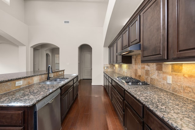 kitchen featuring sink, dark wood-type flooring, dark stone countertops, stainless steel appliances, and dark brown cabinetry